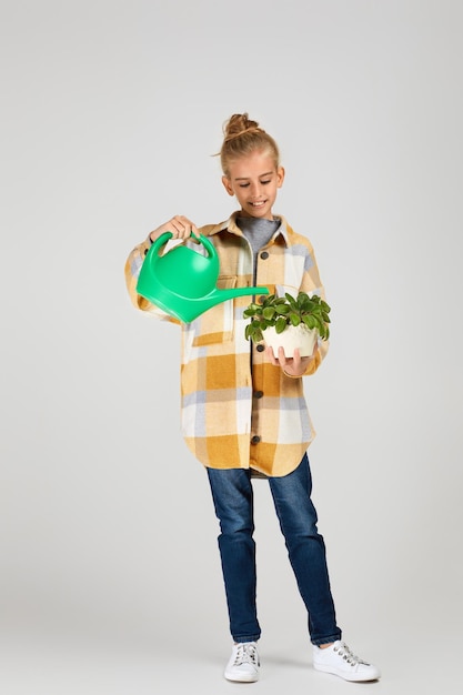 Bambina che innaffia le piante in un vaso di fiori