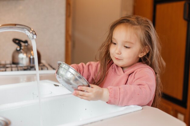 Bambina che lava i piatti nella cucina di una roulotte