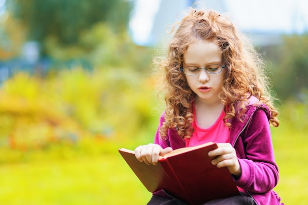 Bambina che legge il libro. Concetto di educazione.