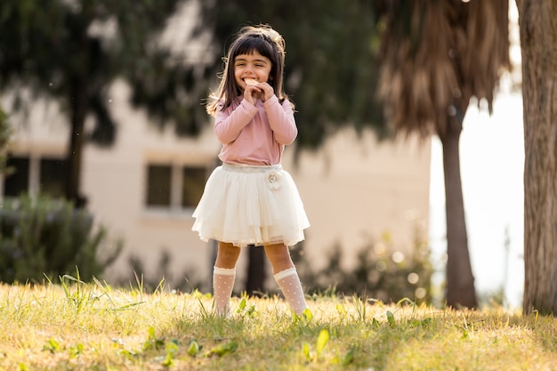 Bambina che mangia i dolci in un parco