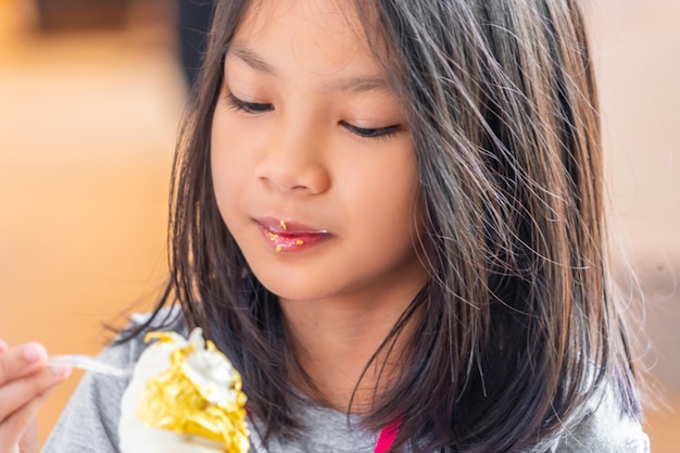 Bambina che mangia il gelato della foglia di oro