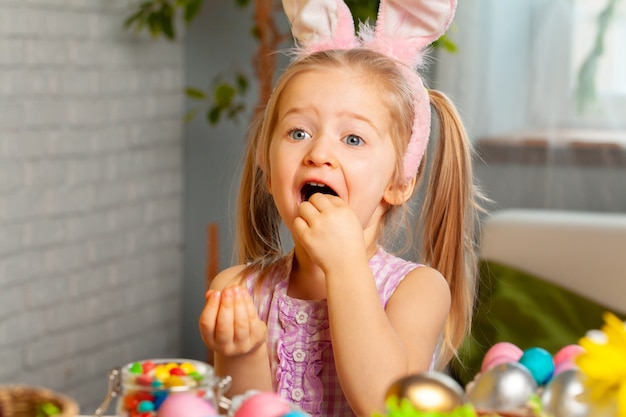 Bambina che mangia le caramelle di Pasqua variopinte