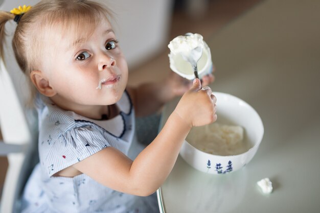 bambina che mangia un cucchiaio di gelato da un piatto