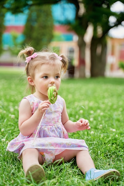 bambina che mangia una deliziosa lecca-lecca su un prato verde