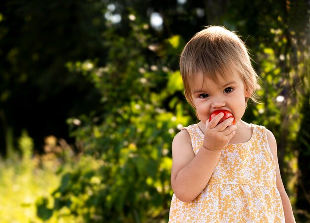 bambina che morde un pomodoro
