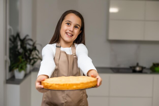 bambina che mostra la torta di mele che ha cotto