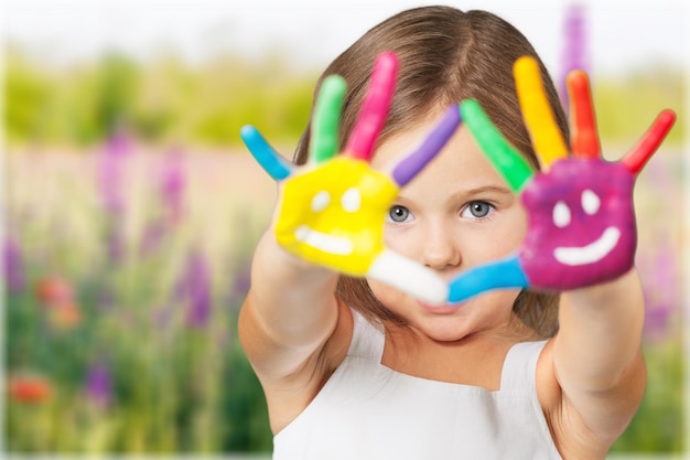 Bambina che mostra le mani dipinte su sfondo luminoso