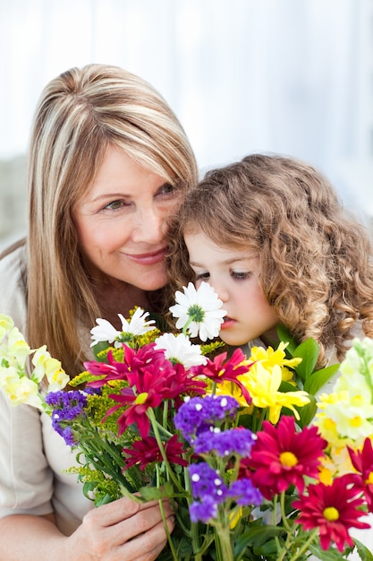 Bambina che odora i fiori mentre sua nonna sta smilling