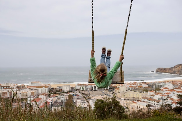 Bambina che oscilla contro la scena della costa di nazare in portogallo