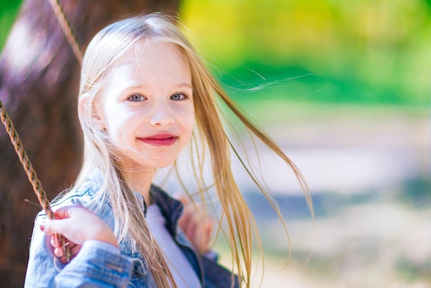 Bambina che oscilla su un'altalena all'aperto nella foresta