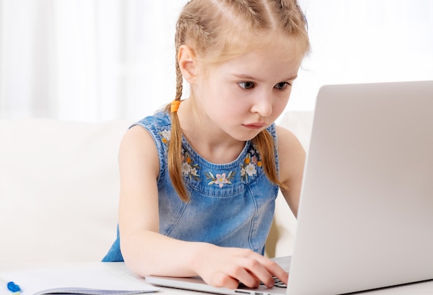 Bambina che per mezzo del suo computer portatile