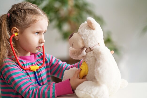 Bambina che per mezzo dello stetoscopio sull'orsacchiotto