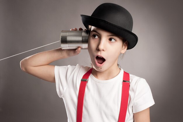 Bambina che per mezzo di una latta come telefono su gray