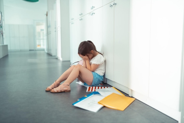 Bambina che piange dopo il terribile primo giorno di scuola con una presa in giro