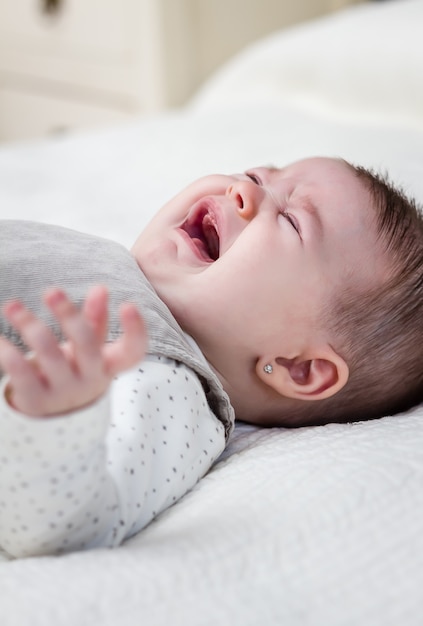 Bambina che piange sul copriletto bianco