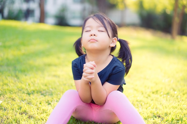 Bambina che prega al mattino al parco.