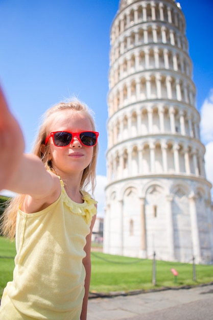 Bambina che prende selfie con la torre a Pisa, Italia