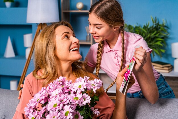 Bambina che presenta fiori a sua madre a casa, momenti felici della vita domestica