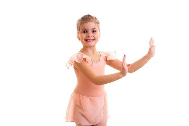 Bambina che ride in abito rosa che balla su sfondo bianco in studio