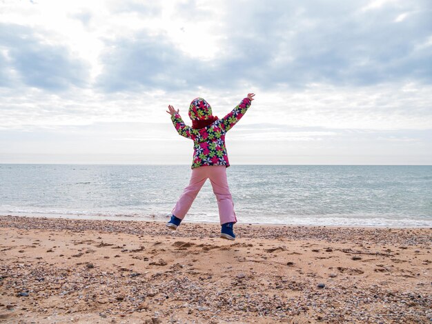 Bambina che salta su una spiaggia di sabbia vuota che vola in aria Stile di vita foto persone reali Paesaggio panoramico Mare blu vivido
