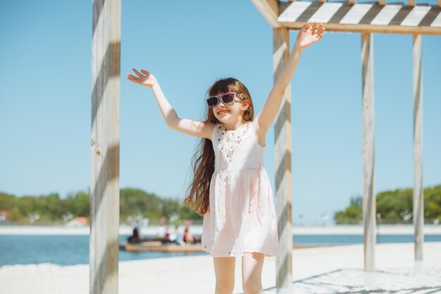 Bambina che salta sulla spiaggia sulla riva della spiaggia della città durante le vacanze estive