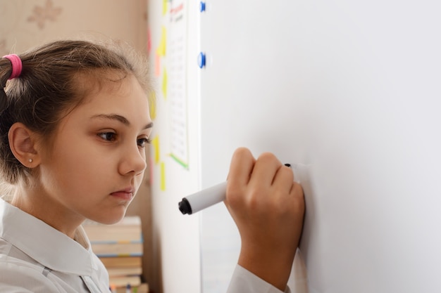 bambina che scrive qualcosa a bordo mentre svolge il compito a casa