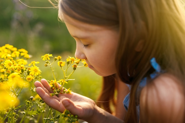 Bambina che sente l'odore di un fiore giallo