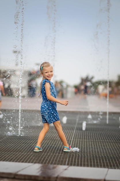 Bambina che si diverte nelle fontane Caldo clima estivo in città Bambina che corre vicino alle fontane nella stagione calda Bambino che corre tra i getti d'acqua delle fontane