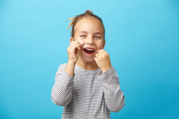 Bambina che si lava i denti con il filo interdentale