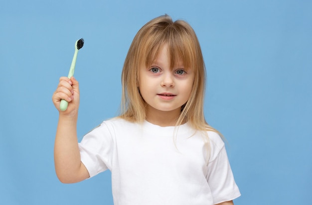 Bambina che si lava i denti e indossa su uno sfondo blu.