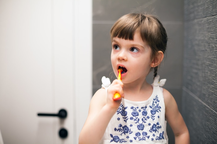 Foto bambina che si lava i denti in un bagno