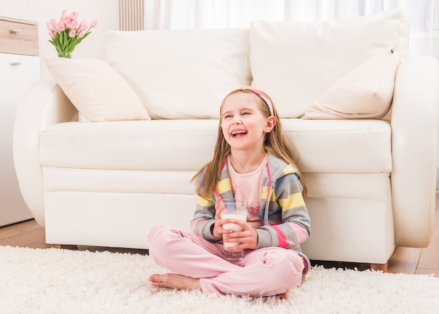 Bambina che si siede con un bicchiere di latte