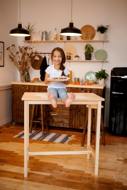 bambina che si siede nella cucina di Natale sul tavolo