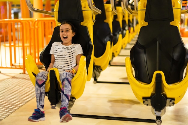 bambina che si siede sull'attrazione nel parco.