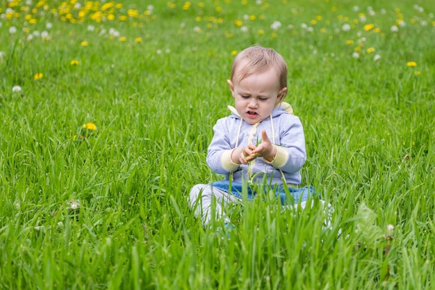 Bambina che si siede sull'erba verde