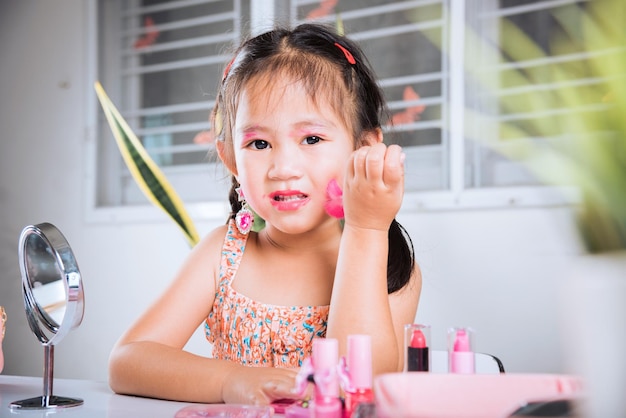 Bambina che si trucca il viso si guarda allo specchio e guancia soffice pennello per cipria