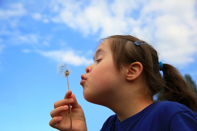 Bambina che soffia il dente di leone