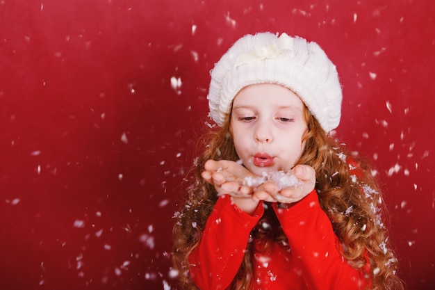 Bambina che soffia neve con la sua mano.