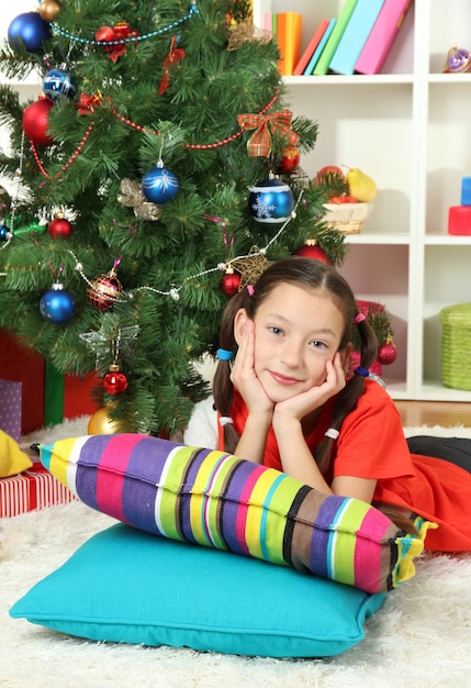 Bambina che sogna vicino all'albero di Natale