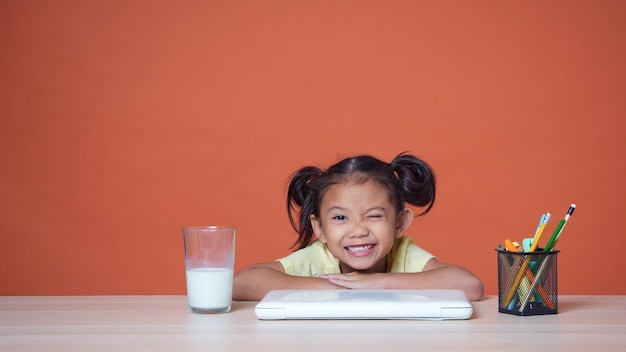 Bambina che studia con il computer portatile