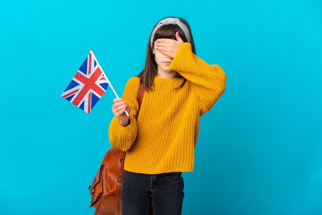 Bambina che studia inglese isolato su sfondo blu che copre gli occhi con le mani. Non voglio vedere qualcosa