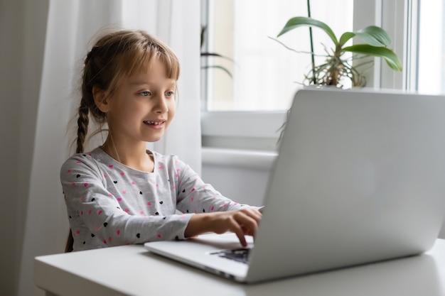 Bambina che studia online usando il suo laptop a casa