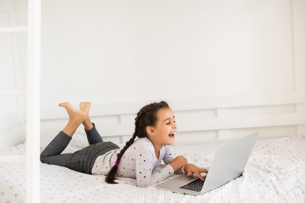 Bambina che studia online usando il suo laptop a casa