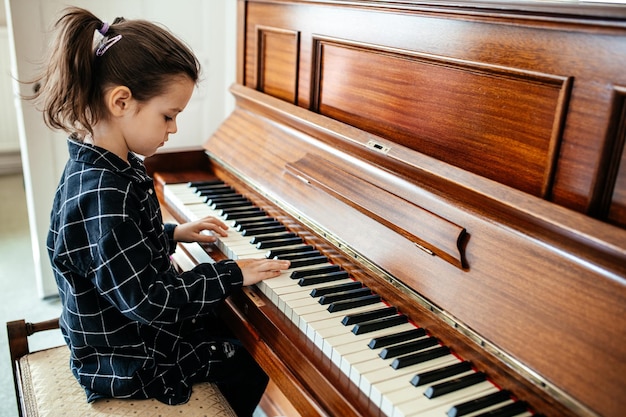 Bambina che suona il bambino di pianto che impara a suonare uno strumento musicale