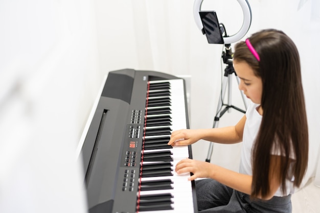 Bambina che suona lo strumento pianoforte a tastiera e gira un video