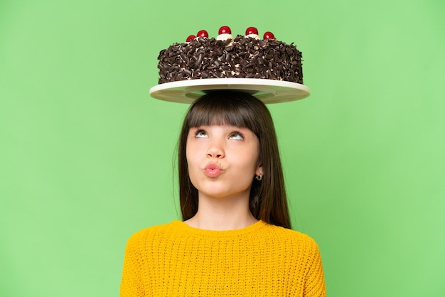 Bambina che tiene la torta di compleanno su sfondo chroma key isolato