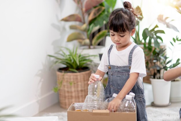 Bambina che tiene le bottiglie di plastica per il riciclaggio