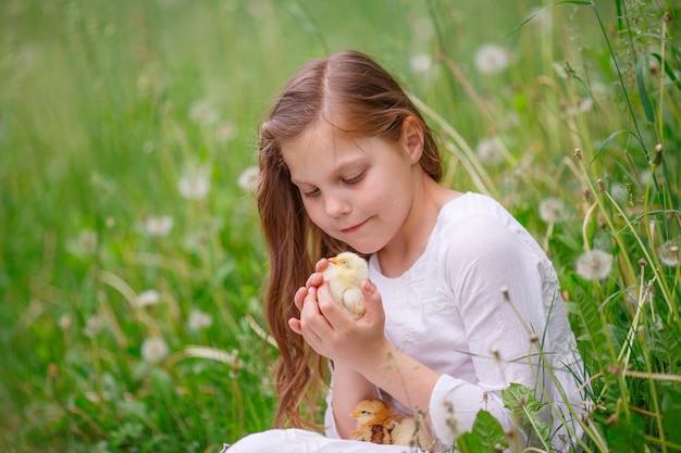 Bambina che tiene le mani di pollo che giocano sull'erba