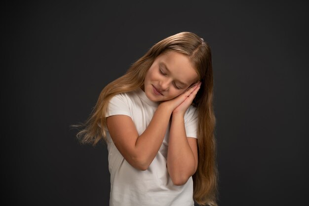 Bambina che tiene le sue mani insieme e si chinò su di loro mostrando che sta dormendo