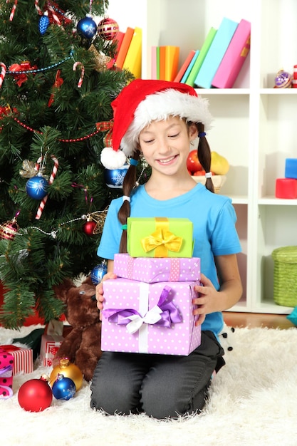 Bambina che tiene scatole regalo vicino all'albero di Natale